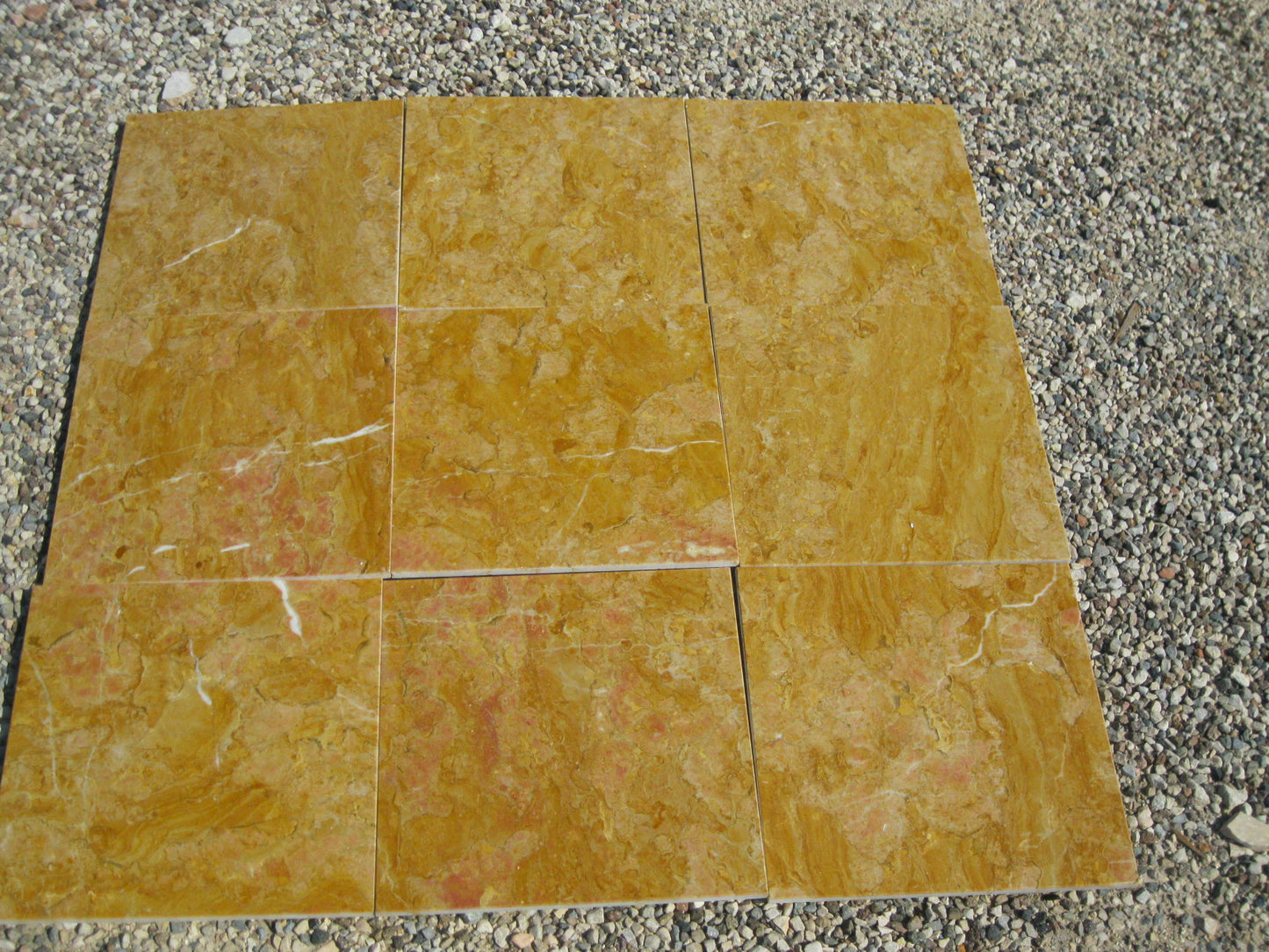 Giallo Reale Natursteinfliesen im Close Up. Die Fliese ist gelb gold mit teils rot-weißer Maserung.