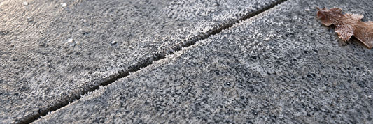Winterlicher Frost breitet sich auf einem Granit aus. Frost kann schädlich sein für Natursteine, hier wird Ihnen gezeigt wie Sie das vorbeugen. 