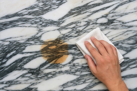 Hand wischt mit Tuch Fleck von Natursteinfläche weg. Wir helfen Ihnen, wir sind Naturstein Tilmes.